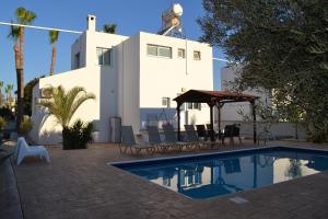 a swimming pool in front of a white building at Makronissos Beach Villas in Ayia Napa