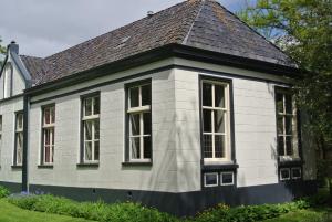 Casa blanca con ventanas y techo en Pastorie Tijdverblijf en Zuidhorn