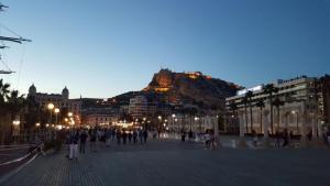 a group of people walking around a city with a mountain at First line Apartment in Alicante