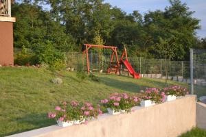 a garden with a playground with flowers in a yard at Berezdtető Vendégház in Cserépfalu