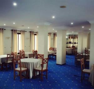 una sala da pranzo con tavoli, sedie e bottiglie di vino di Hotel Zelis a Asilah
