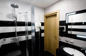 La salle de bains en noir et blanc est pourvue d'un lavabo et d'une douche. dans l'établissement Novobilski - obok Termy Bania, à Białka Tatrzańska