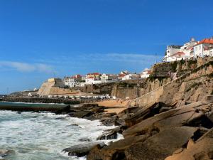 a beach with rocks and houses on a cliff at Ericeira Surf and Sun in Ericeira