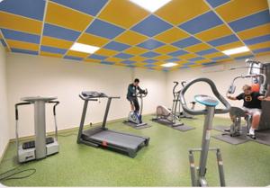 une salle de sport avec plusieurs personnes faisant de l'exercice sur des tapis de course dans l'établissement Prim Hotel Reims, à Witry-lès-Reims