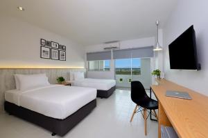 a hotel room with two beds and a desk and a television at Ruenthip Pattaya in North Pattaya