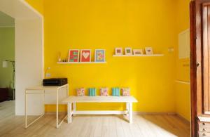a yellow room with a bench and a table at Casetta di Cleo in Papigno