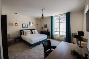 a bedroom with a bed and a table and a window at Hôtel Le Chantilly in Chantilly