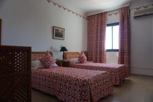 1 dormitorio con 2 camas y ventana en Hotel Zelis, en Asilah