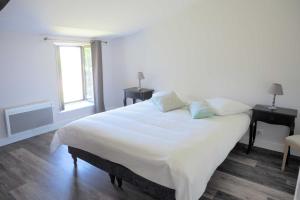 Un dormitorio blanco con una cama grande y una ventana en Hameau de La Landrière à 3 min du Puy du Fou en Saint-Malo-du-Bois