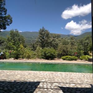 una piscina de agua verde con montañas al fondo en Hotel Rural Casa Alfayales-Only Adults, en Poyales del Hoyo