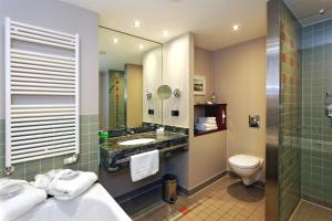 a bathroom with a sink and a toilet and a mirror at Hotel Kaliebe in Trassenheide