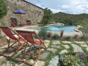 a pair of chairs and an umbrella in front of a pool at Mas de la Fariole in Caixas