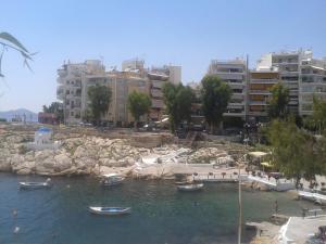 um grupo de barcos em uma massa de água com edifícios em Super 36sqm Junior Suite in luxurious picturesque area em Piraeus