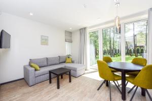 a living room with a couch and a table and chairs at Sakalo 44 in Palanga