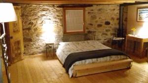 una camera con letto e parete in pietra di B&B Sasso Bianco a Prata Camportaccio