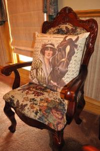 a chair with a painting of a woman riding a horse at Queen Anne Bed and Breakfast in Nevada