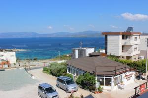 a building with two cars parked in a parking lot at Huzur Hotel in Siğacık