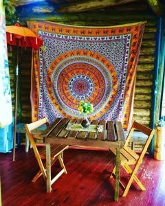 Ein Tisch und Stühle vor einer Wand mit einem Teppich in der Unterkunft Pousada Ananda in Osório
