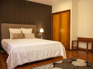 a bedroom with a large white bed with a wooden door at Varzim Guesthouse in Póvoa de Varzim