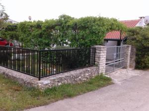 a black metal fence with a stone wall at Apartment Milka in Petrcane