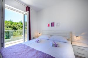 a bedroom with a white bed with a large window at Villa Niki 2 in Cavtat