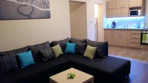 salon z czarną kanapą i niebieskimi poduszkami w obiekcie Tahiti apartman w Hajduszoboszlo
