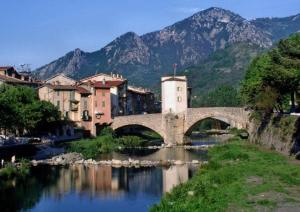 a bridge over a river in a town with mountains at Apartment Des Romains in Sospel