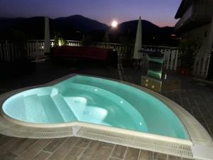 a large blue swimming pool on a patio at night at Hotel La Compagnia Del Viaggiatore in LʼAquila
