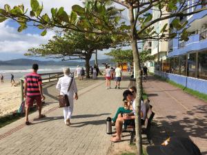 un grupo de personas sentadas en un banco en la playa en Cobertura Silva E Silva, en Meia Praia