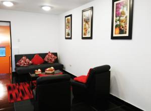 a living room with a black couch and red pillows at White Hope Apartment in Lima +12 photos
