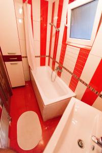 ブカレストにあるルーフトップ テラス アパートメントの赤と白のバスルーム(バスタブ、シンク付)