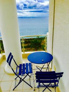 einen Balkon mit einem blauen Tisch, Stühlen und Meerblick in der Unterkunft White Residence Apartament in Sarandë