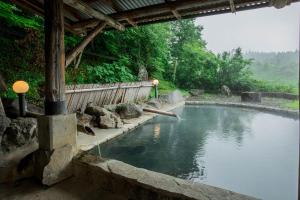 a large pool of water with a fence and trees at Oogi Onsen Oogiso in Minamioguni