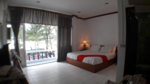 a bedroom with a bed and a large window at Tony Home and Restaurant in Karon Beach