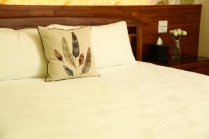 1 cama con sábanas blancas, almohada y mesa en When the Swallow Flying B&B, en Taitung