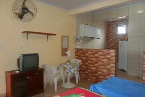a living room with a small table and a tv at Quitinetes dos Ipês in Barra de São João