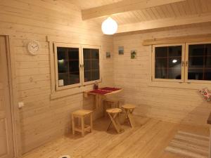 a room with a wooden wall with a table and two stools at Kāpas in Melnsils +4 photos