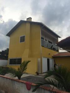 a yellow house with a balcony in front of it at Sobrado Itapoá in Itapoa