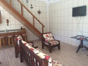 a living room with two chairs and a staircase at Sobrado Itapoá in Itapoa
