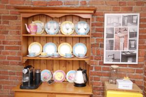 a shelf filled with plates and bowls on a brick wall at Hillside Cottage Berrima in Berrima