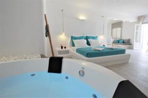 a white room with two beds and a bath tub at Yades Suites & Spa - Adults only in Naousa