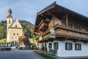 a building with a clock on it next to a church at Pension Sunnberg in Going am Wilden Kaiser