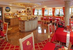 a restaurant with red tables and chairs and a kitchen at Pension Sunnberg in Going am Wilden Kaiser