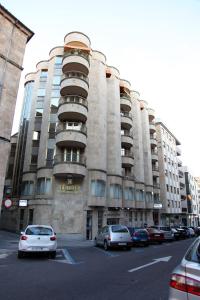 un gran edificio con coches estacionados en un estacionamiento en Hostal Santel San Marcos, en Salamanca