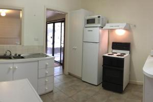 a kitchen with a white refrigerator and a microwave at The Ledge Holiday House in Halls Gap