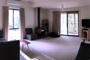 ein Wohnzimmer mit einem Sofa, einem TV und Fenstern in der Unterkunft The Ledge Holiday House in Halls Gap