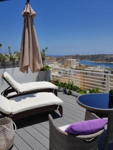 a balcony with chairs and an umbrella and a table at Paulos Valletta in Valletta