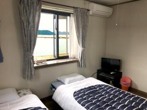 a bedroom with a bed and a window and a television at Guest House Seaside Namihei in Naoshima
