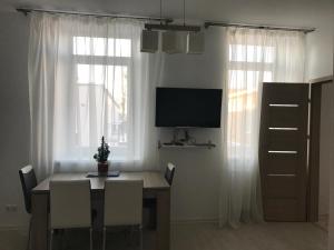 ein Esszimmer mit einem Tisch mit Stühlen und einem TV in der Unterkunft Taikos Apartmentai 2 in Druskininkai