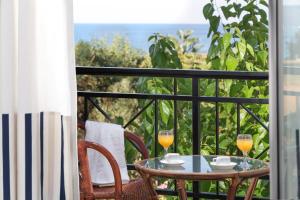 a table with two glasses of orange juice on a balcony at Iris Beach Hotel in Monemvasia